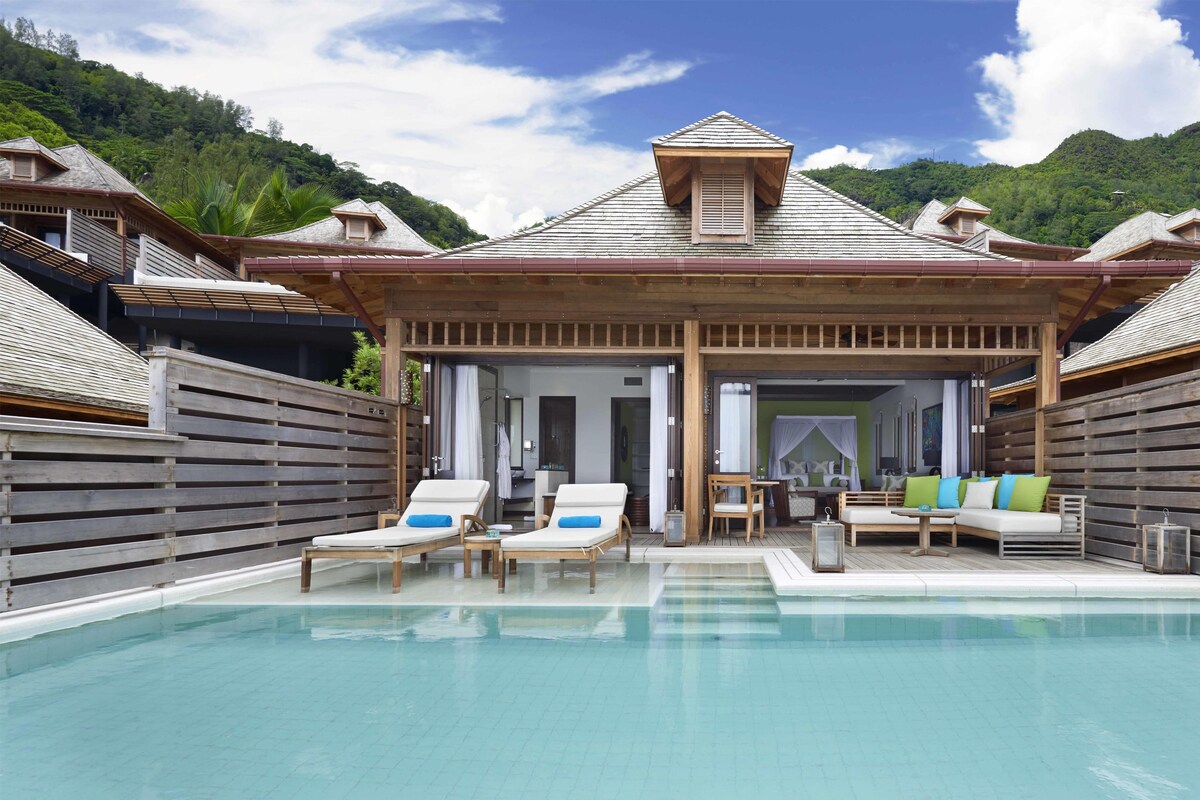 A pool area with lounge chairs and a wooden pergola.