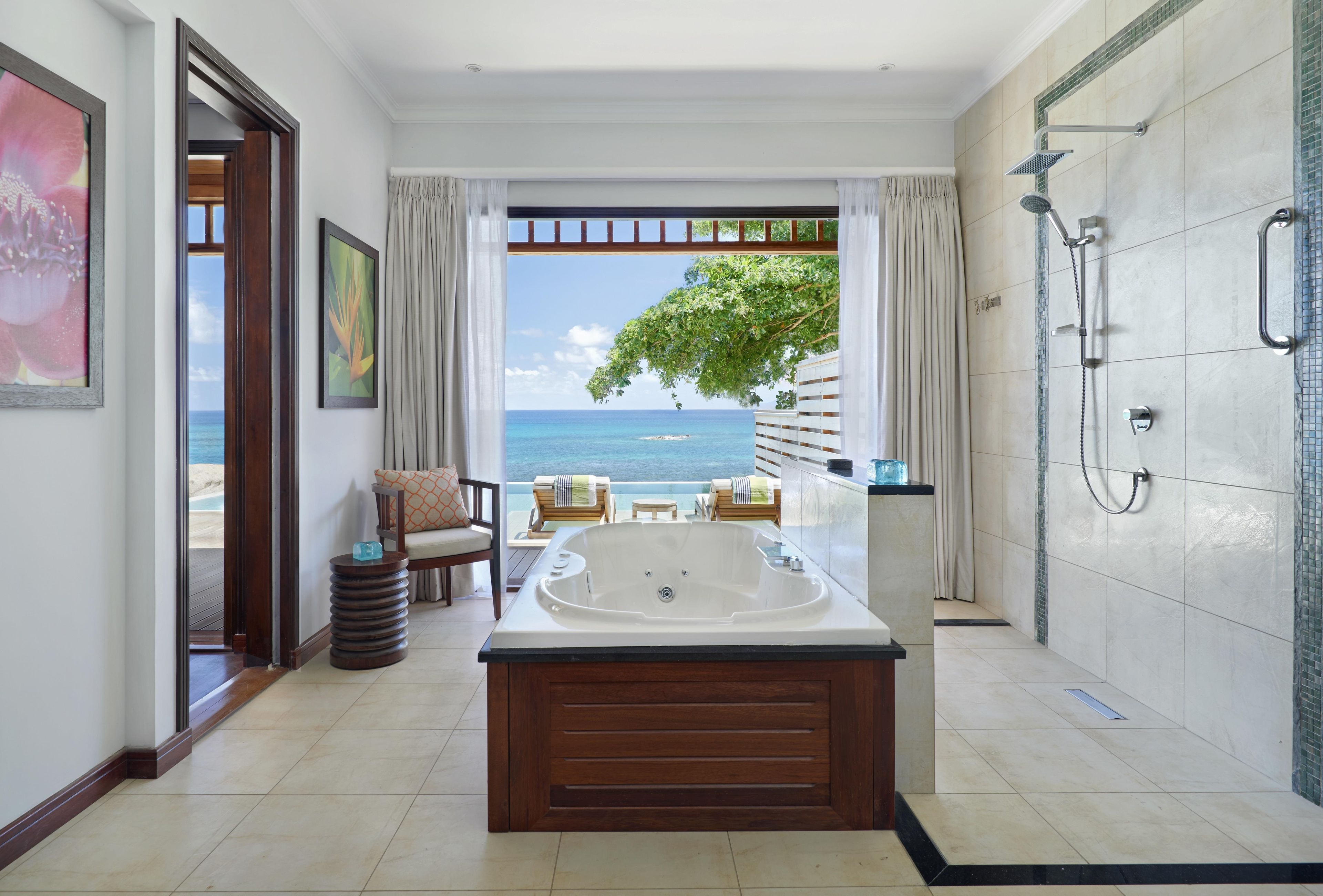 Ein Badezimmer mit einer großen Badewanne, einer Dusche und Meerblick.