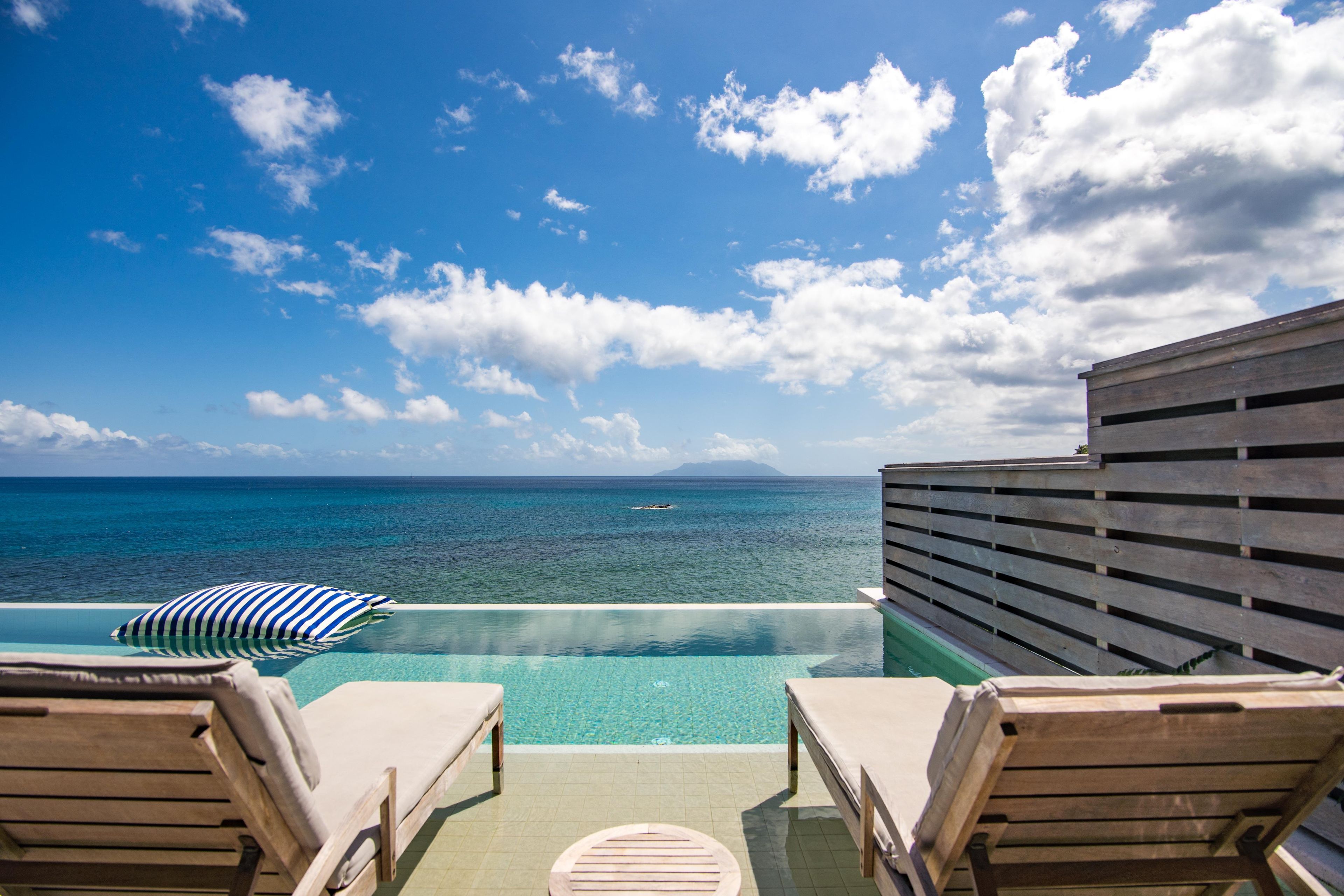 Vista da piscina com espreguiçadeiras e vista para o oceano.