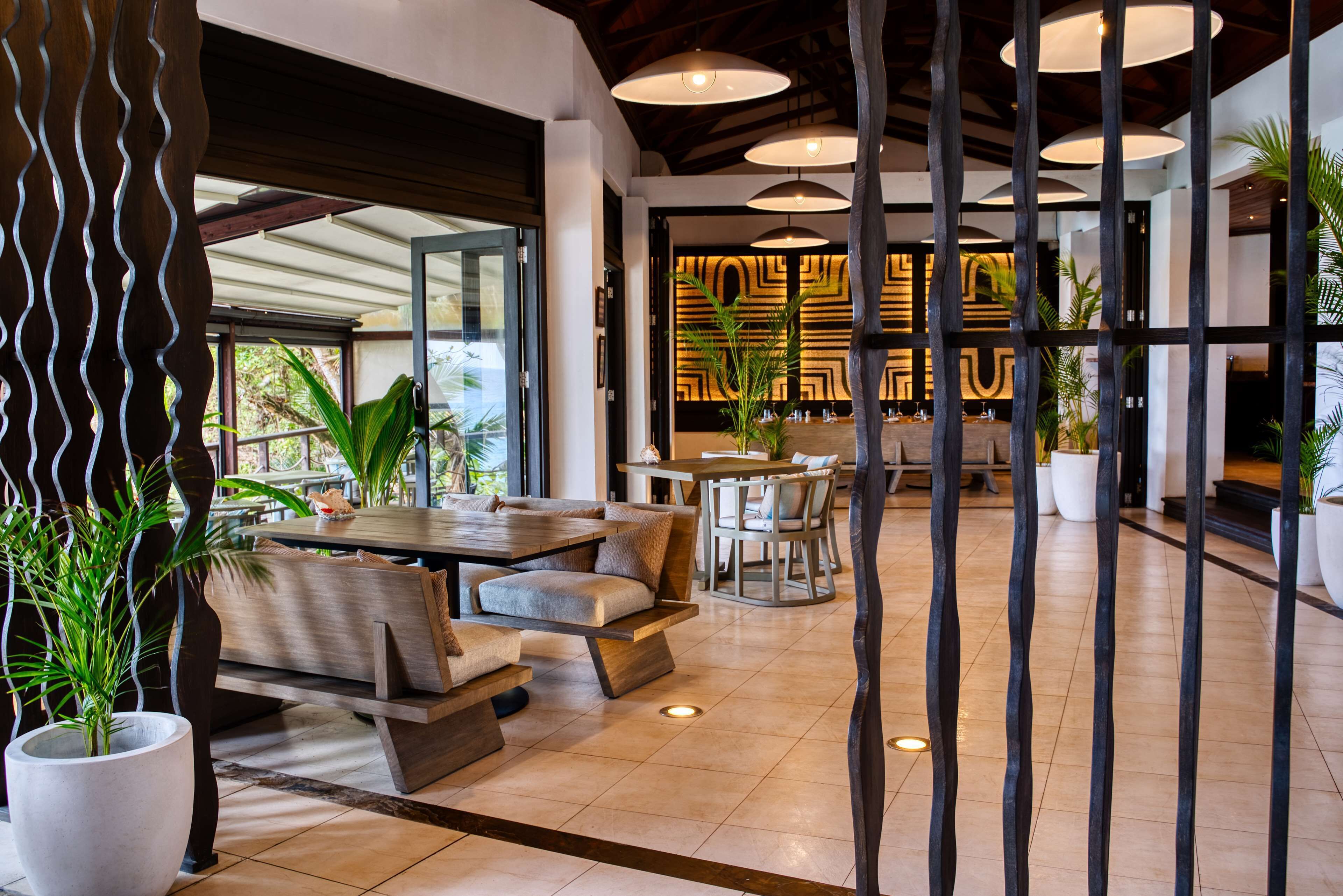 A modern indoor space with a dining area, seating arrangements, and a decorative wall with geometric patterns.