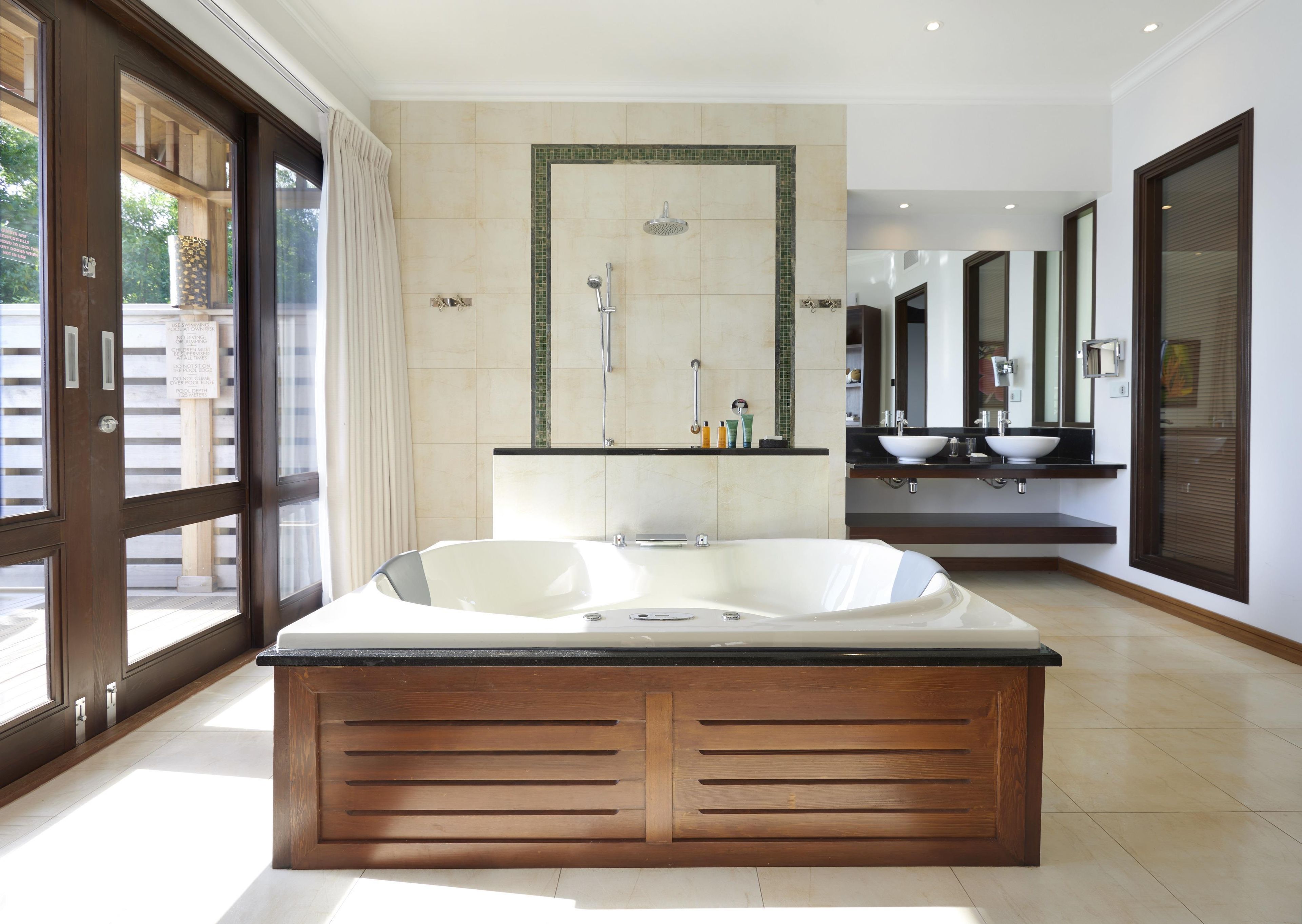 A modern bathroom with a large bathtub, a shower area, and a vanity with a sink and mirror.