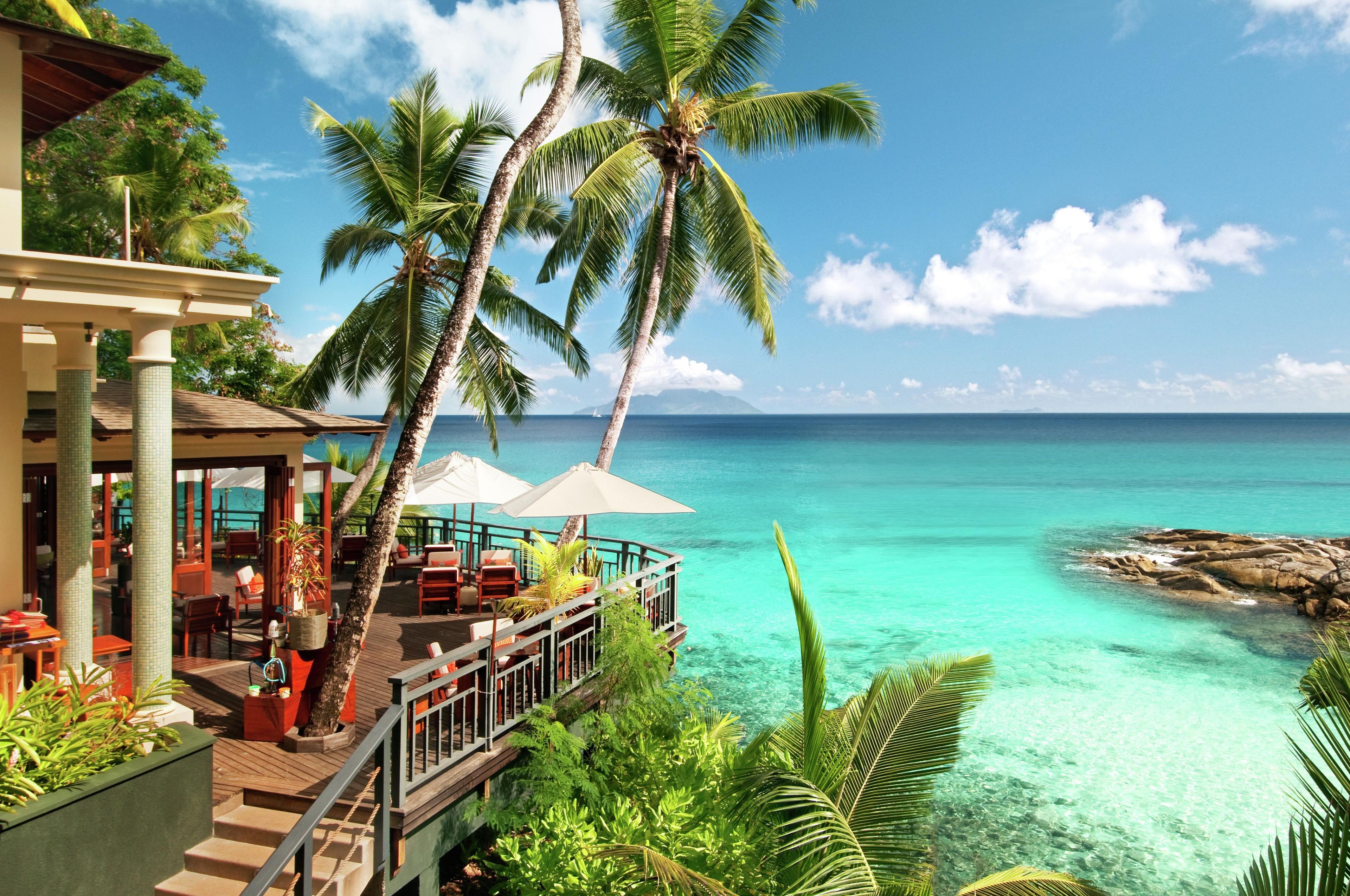 A resort with a wooden deck, outdoor seating, and a view of the ocean.