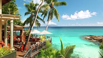 A resort with a wooden deck, outdoor seating, and a view of the ocean.