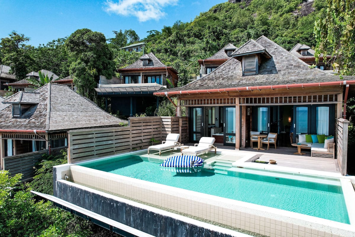 Ein Resort mit Swimmingpool, Liegestühlen und Blick auf den umliegenden Wald.