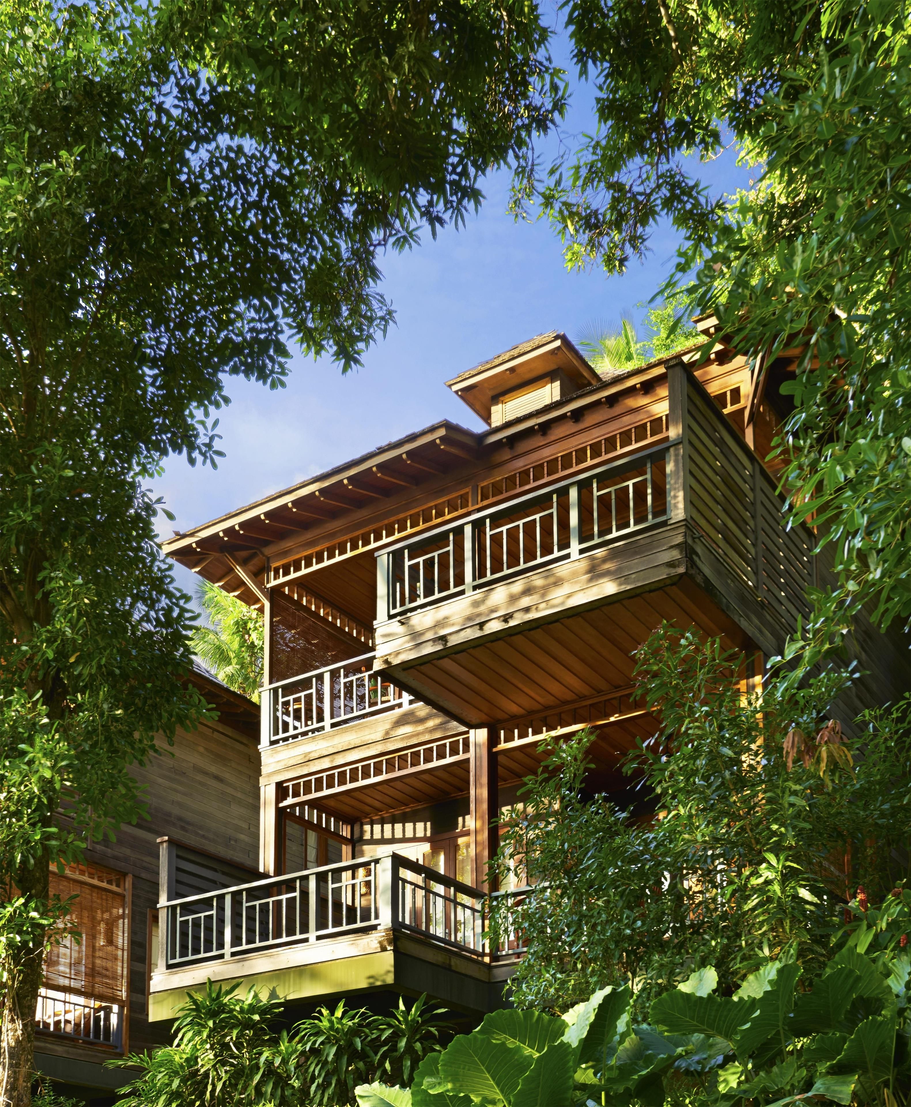 A multi-story wooden building with balconies, surrounded by lush greenery.