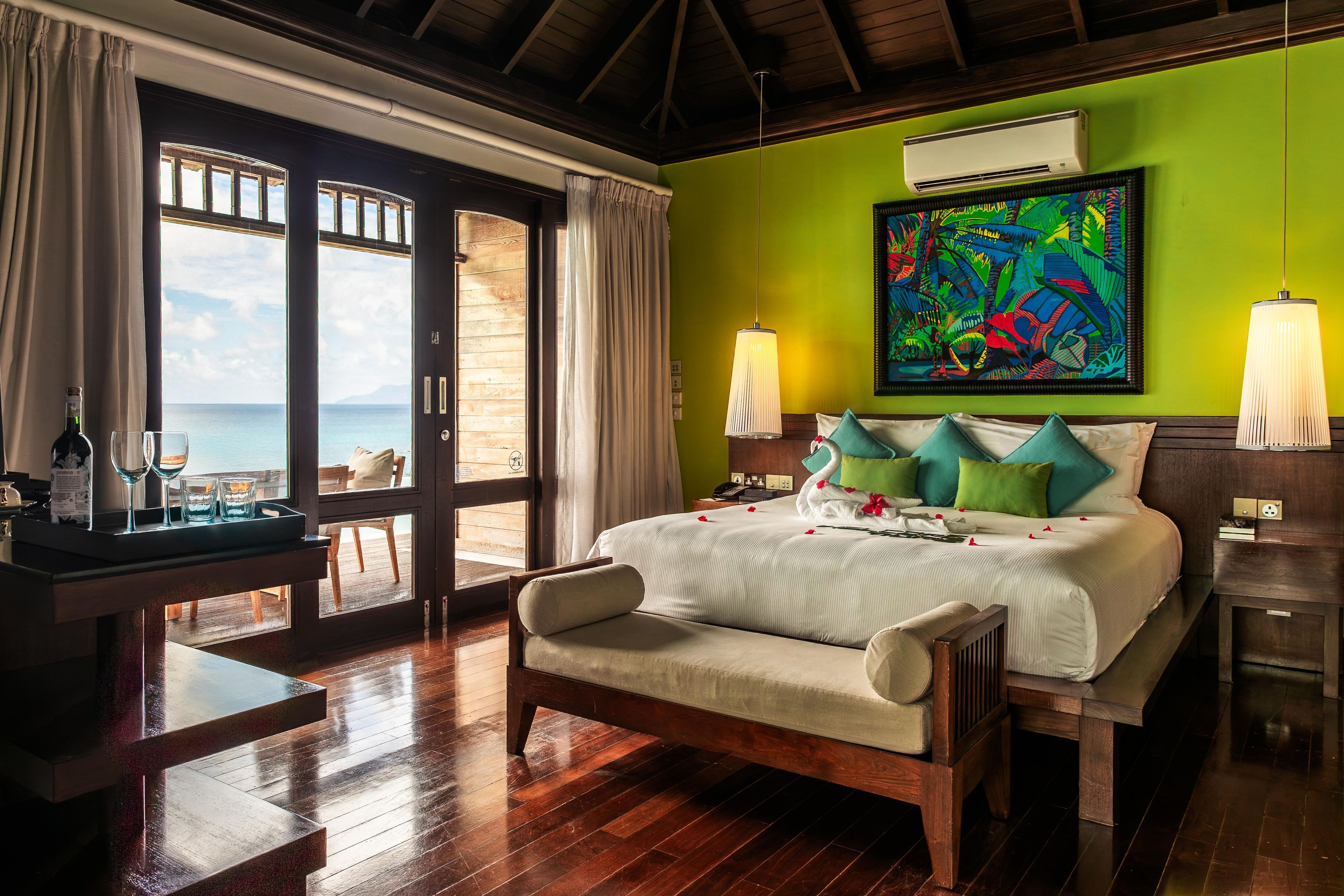 A hotel room with a bed, a desk, and a view of the sea.