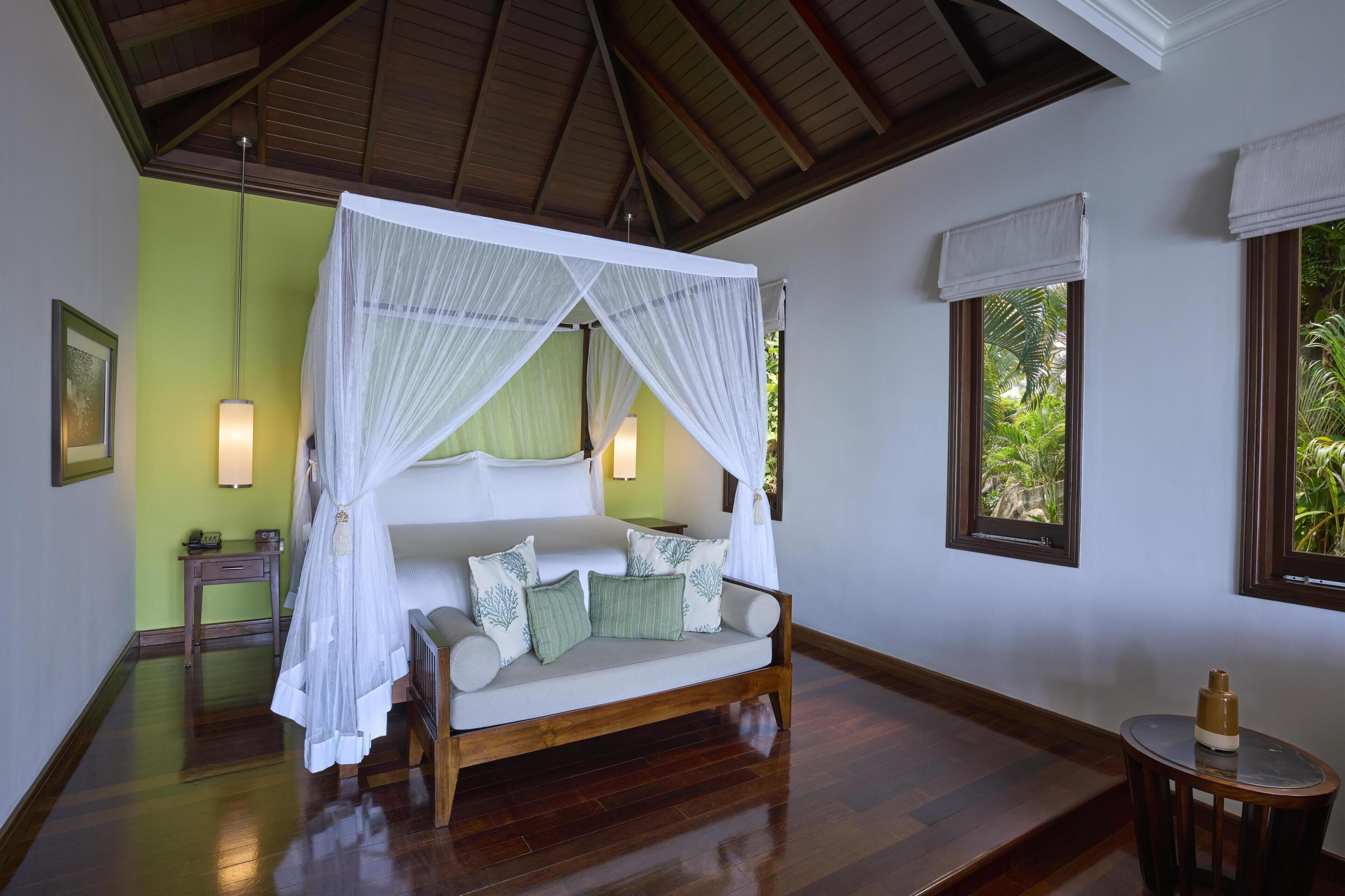 A room with a four-poster bed, a small table, and a nightstand.