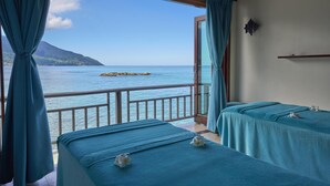 Ein Zimmer mit zwei Betten, Meerblick und einem Balkon mit Geländer.