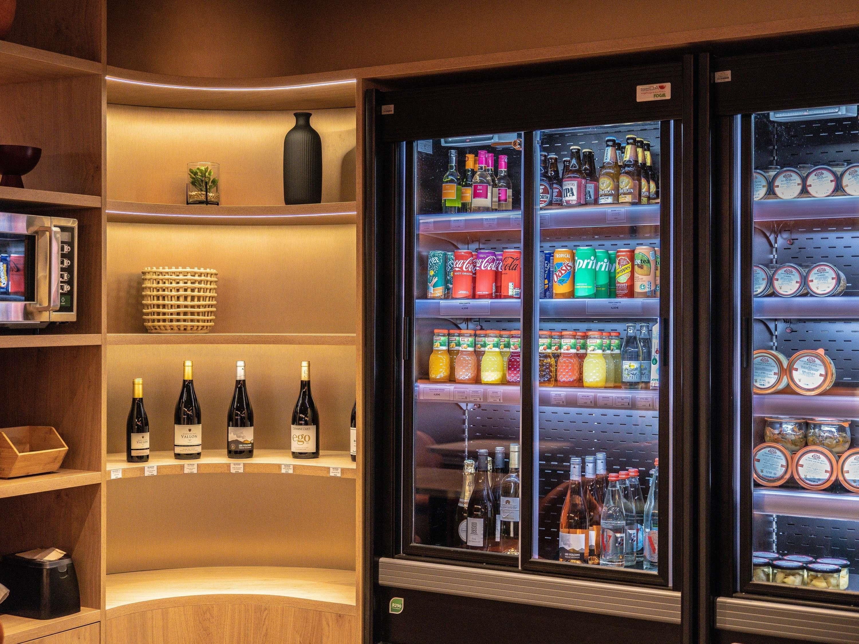 Mini-bar com diversas bebidas, incluindo vinho, cerveja e refrigerantes.