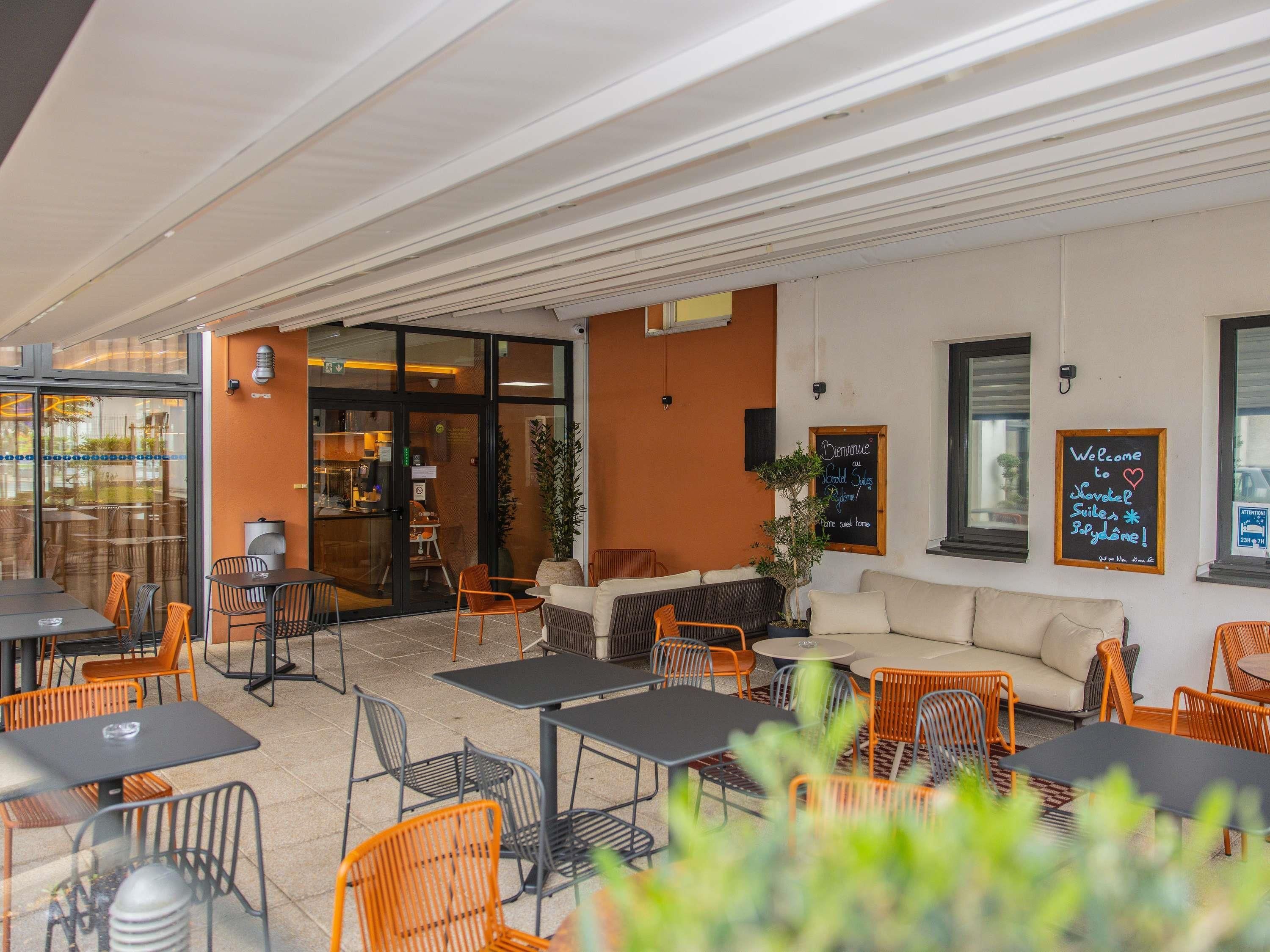 An outdoor seating area with tables and chairs, a sofa, and a potted plant.