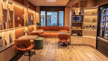 Een modern interieur met een zithoek, tafels en een koelkast vol drankjes.