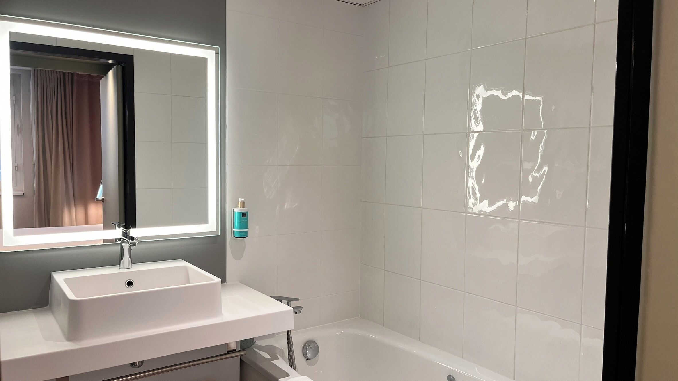 A bathroom with a white sink, a mirror, and a bathtub.