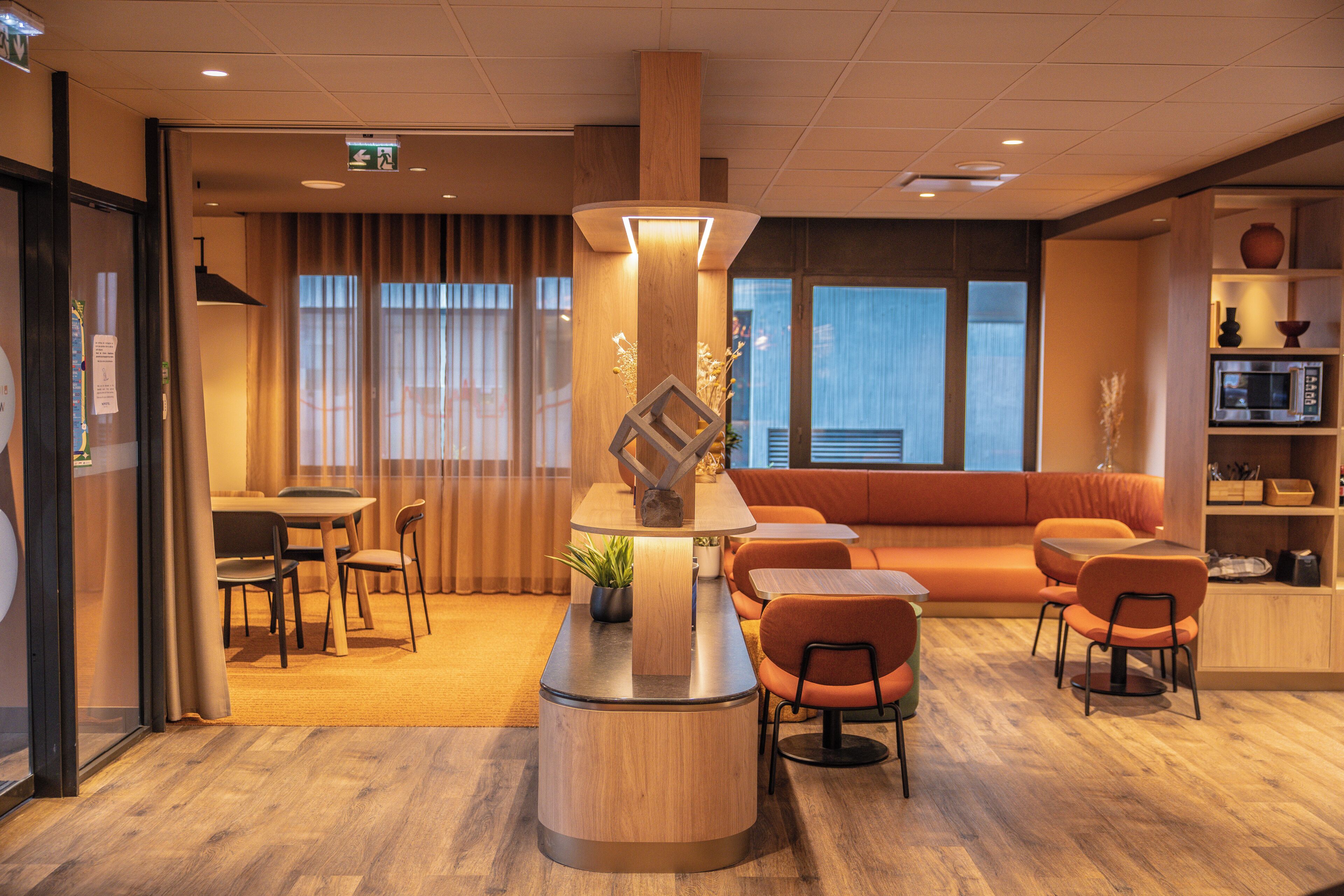 Un vestíbulo moderno de hotel con mostrador de recepción, zona de estar y un amplio ventanal.