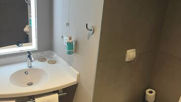 Ein modernes Badezimmer mit Waschbecken, Spiegel, Handtuchhalter, Toilette und Mülleimer.