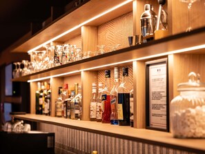 A bar area with shelves of liquor bottles and glasses. - Novotel Suites Clermont Ferrand Polydome (Clermont-Ferrand)