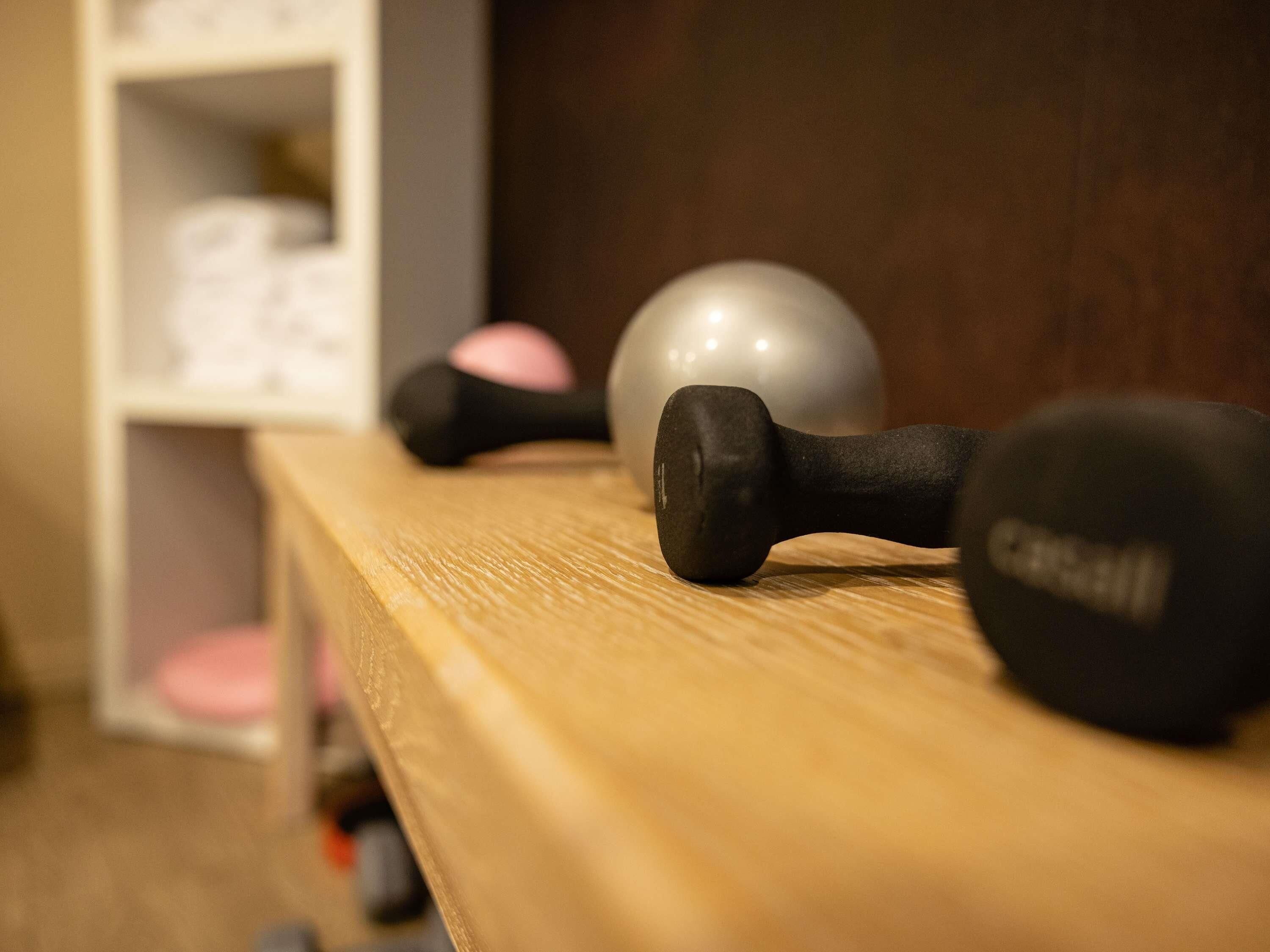 A wooden shelf with dumbbells and a medicine ball.