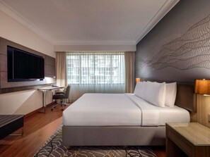 A hotel room with a bed, desk, chair, TV, and a large window with curtains. - Novotel Kuala Lumpur City Centre (Kuala Lumpur)