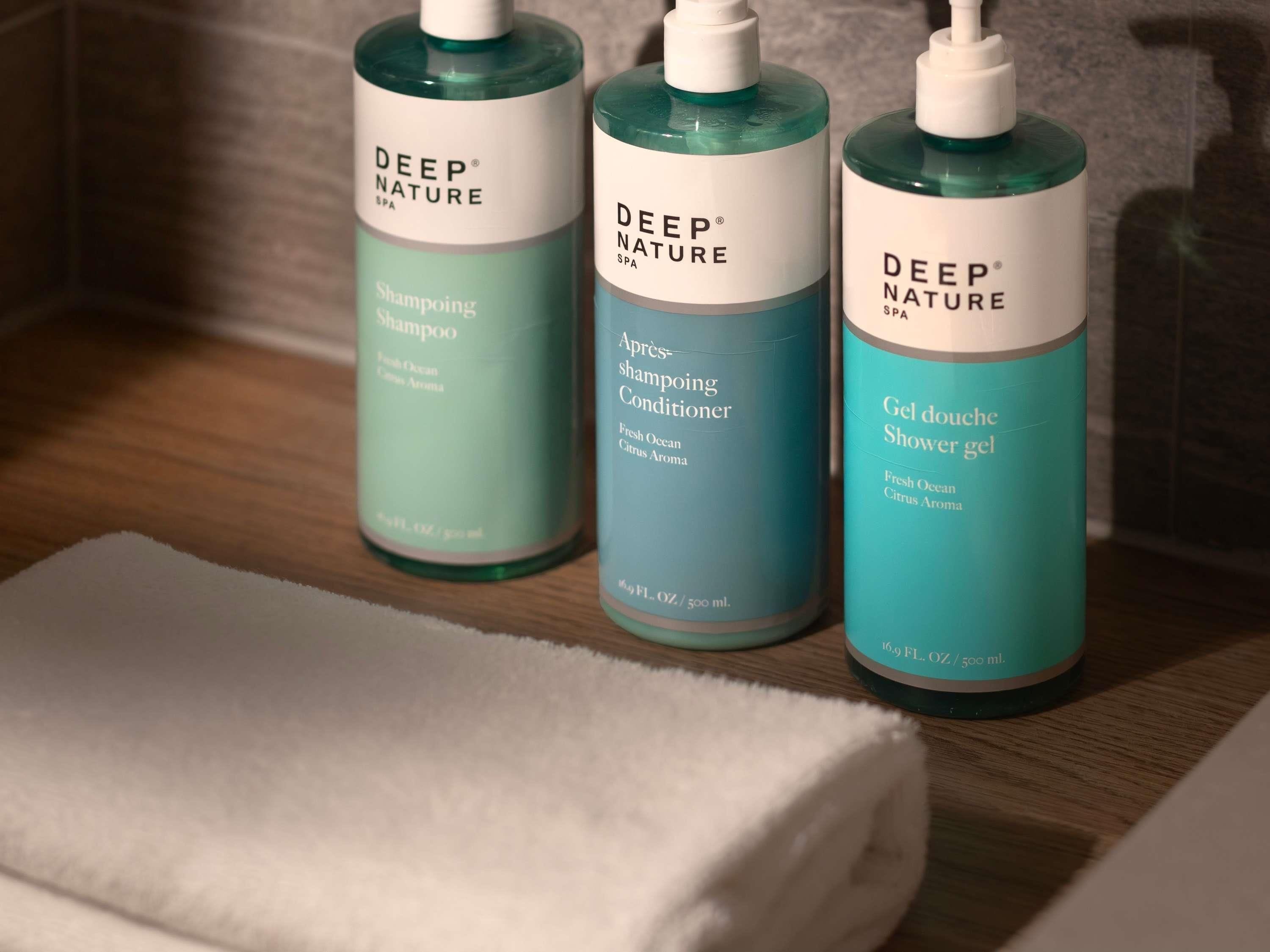 Três frascos de produtos Deep Nature para spa sobre uma superfície de madeira.