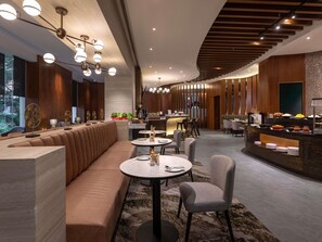 A modern restaurant with a long counter, seating area, and decorative ceiling lights.