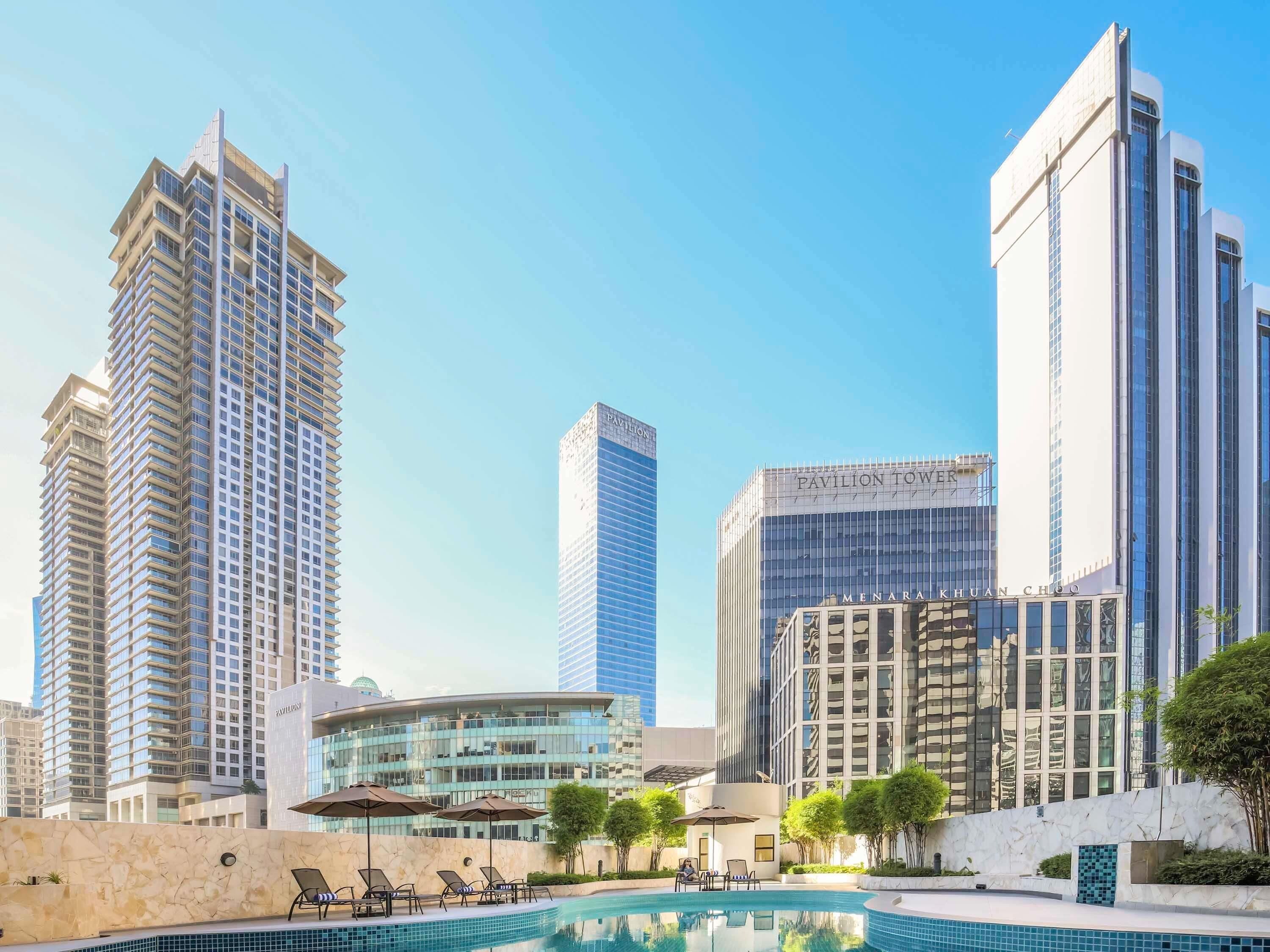 Un hotel moderno con piscina, rodeado de edificios altos.