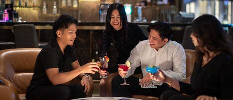 A group of people seated around a round table in a bar area with a bar in the background.