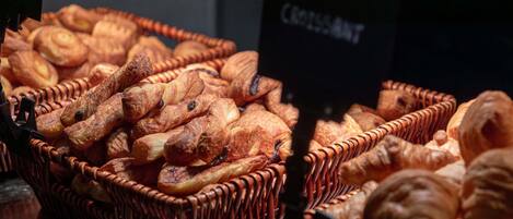 A display of baked goods, including croissants and other pastries, arranged in wicker baskets.