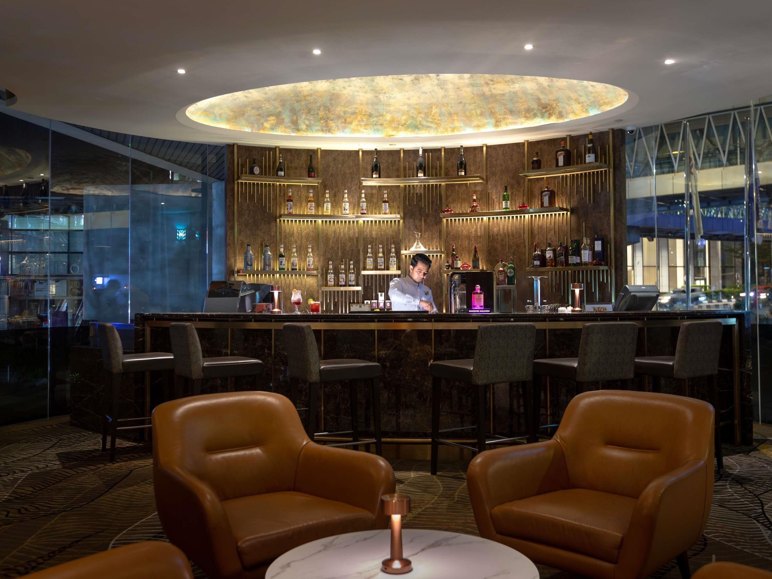 A bar area with leather chairs, a bartender, and a well-stocked bar.