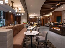 Un restaurante moderno con una barra alargada, zona de asientos y lámparas decorativas en el techo.
