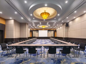 A conference room with a long table, black chairs, a projector screen, and a carpeted floor. - Novotel Kuala Lumpur City Centre (Kuala Lumpur)