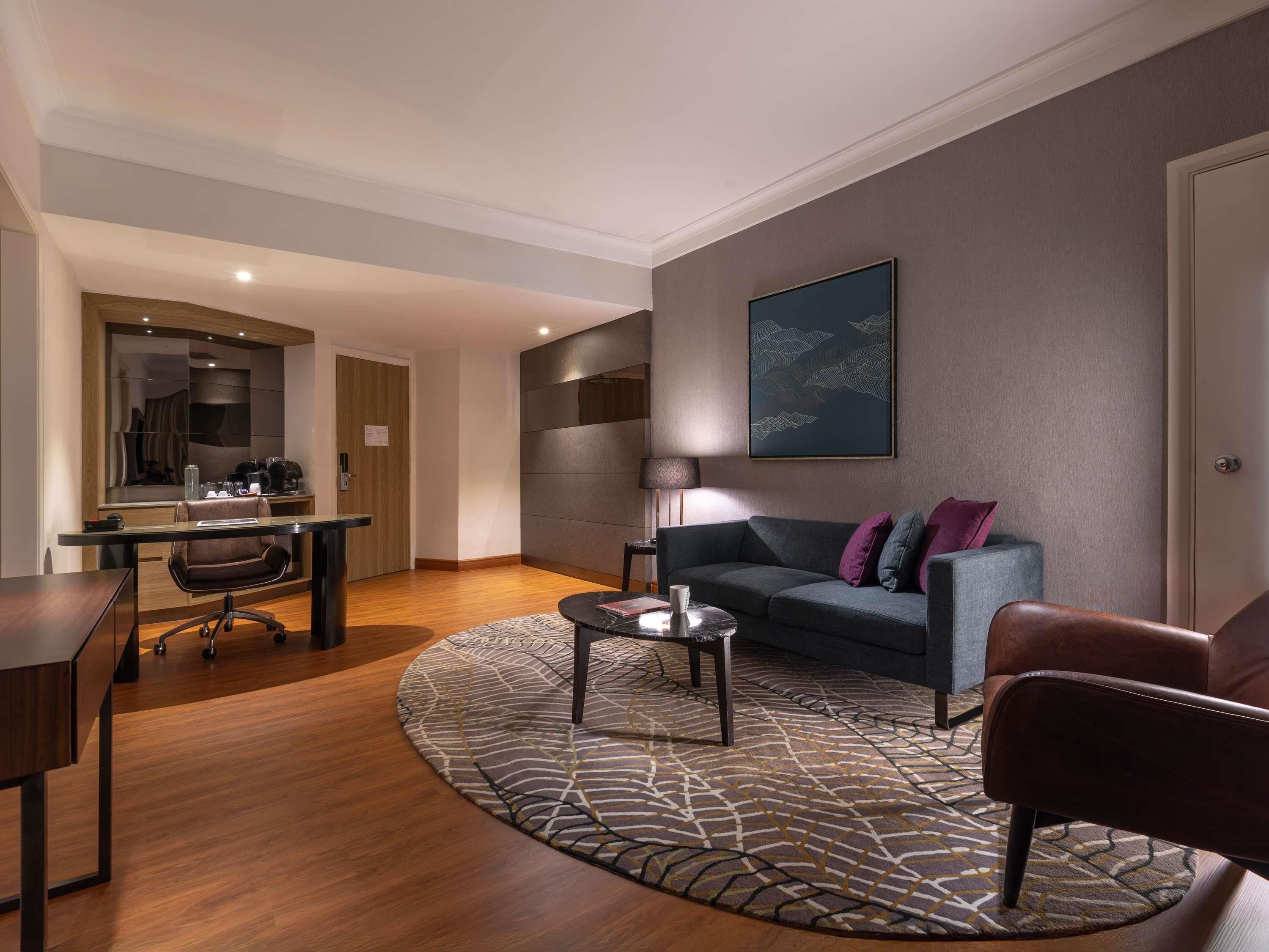 A modern living room with a sofa, coffee table, and a desk with a chair.
