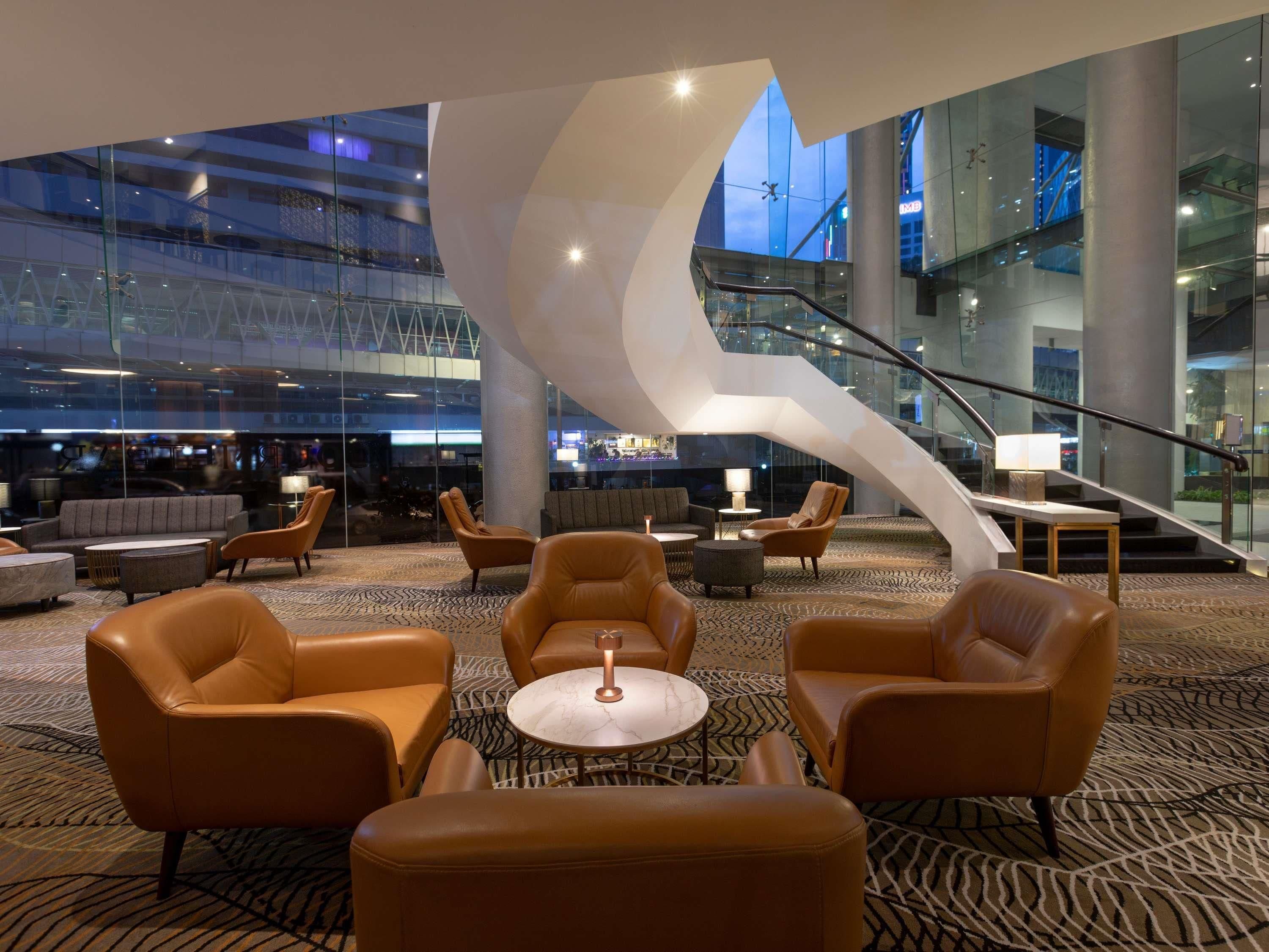 A modern lobby with leather sofas, a coffee table, and a spiral staircase.