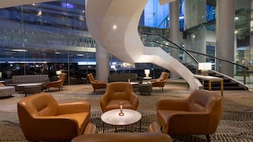A modern lobby with leather sofas, a coffee table, and a spiral staircase.