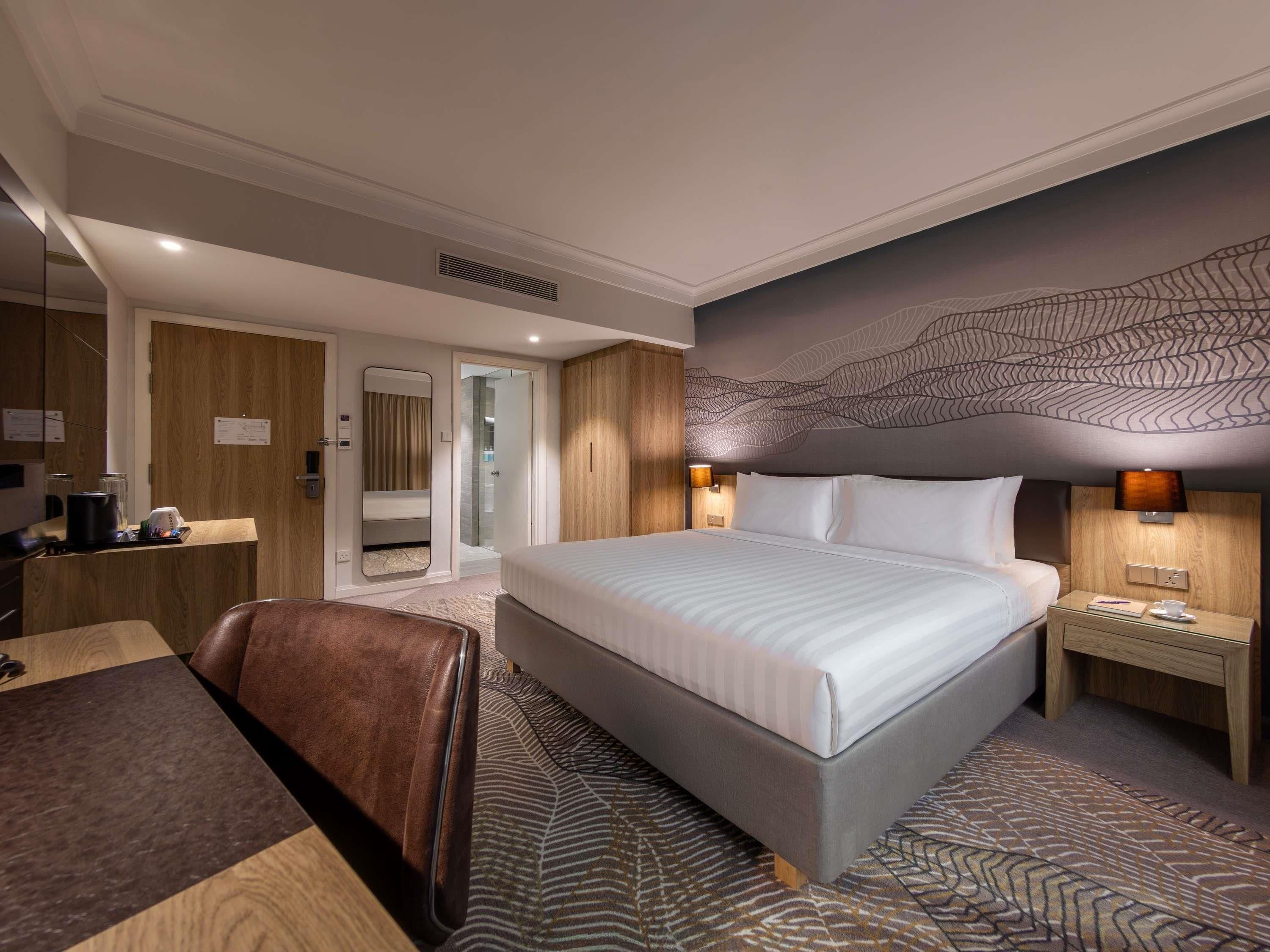 Camera d'albergo con un letto grande, una scrivania, una sedia, uno specchio, un armadio e un bagno.