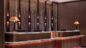 A reception area with a marble counter, two lamps, and a patterned carpet. - Novotel Kuala Lumpur City Centre (Kuala Lumpur)