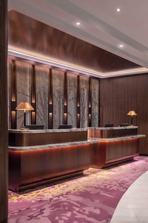 A reception area with a marble counter, two lamps, and a patterned carpet. - Novotel Kuala Lumpur City Centre (Kuala Lumpur)