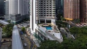 A high-rise hotel with a pool, surrounded by other buildings and a busy street. - Novotel Kuala Lumpur City Centre (Kuala Lumpur)