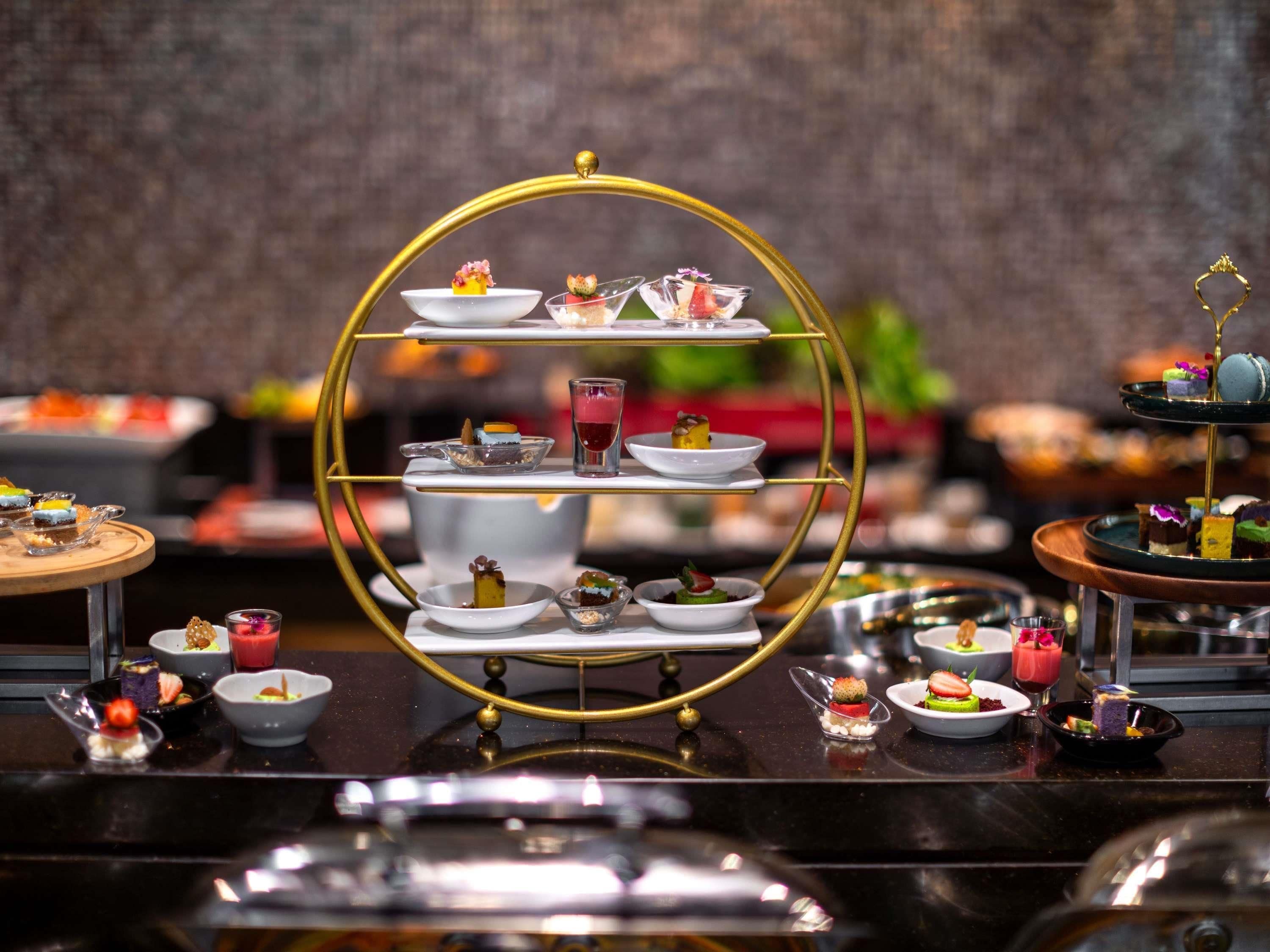 A multi-tiered dessert display with various plated desserts and drinks.