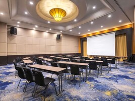 Une salle de conférence équipée d’un grand écran, de plusieurs tables et de chaises.