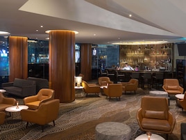 A modern bar area with leather seating, a bar counter, and a city view.