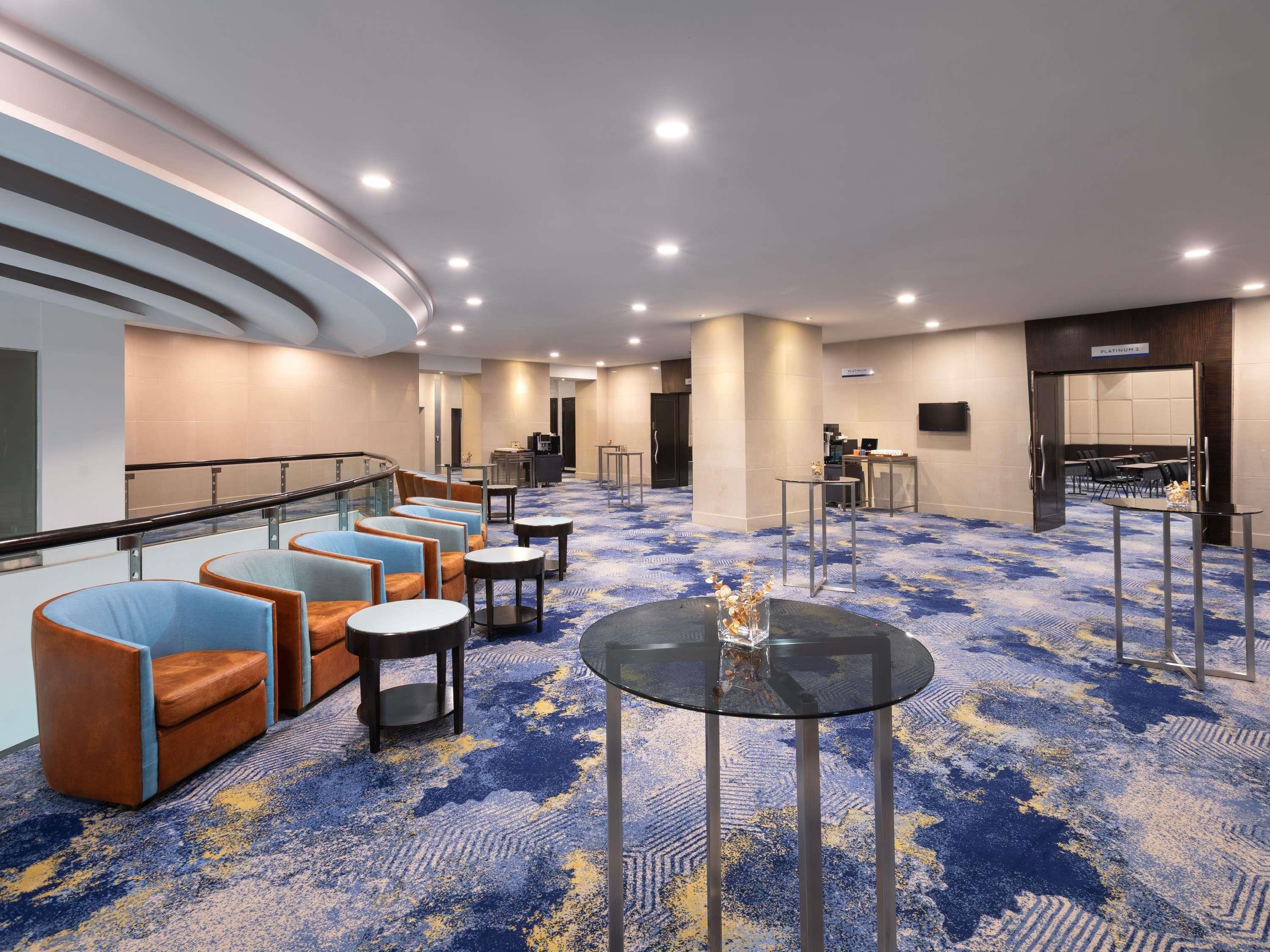Un vestíbulo de hotel con áreas de estar, una recepción y una sala de conferencias.