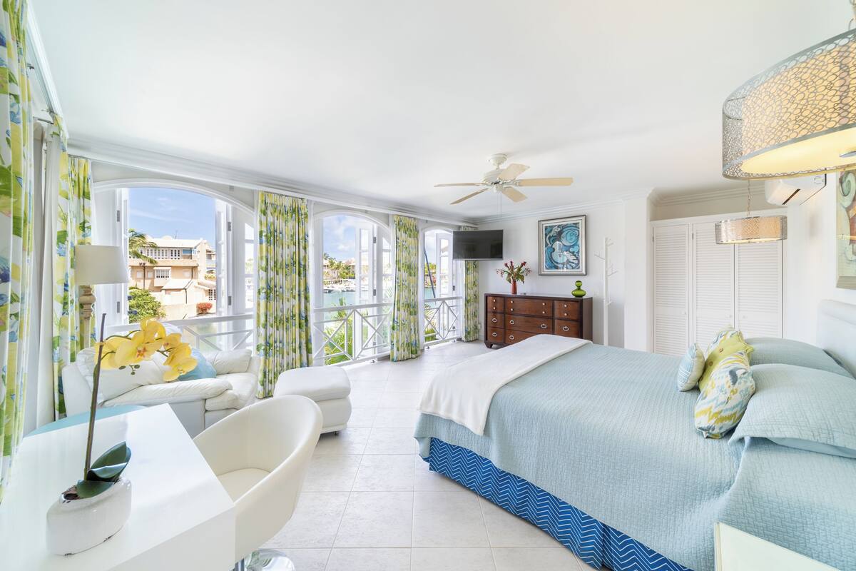 Habitación de hotel con balcón, cama, escritorio y televisor.
