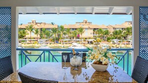 Un balcón con vista a una piscina, palmeras y edificios de un resort.