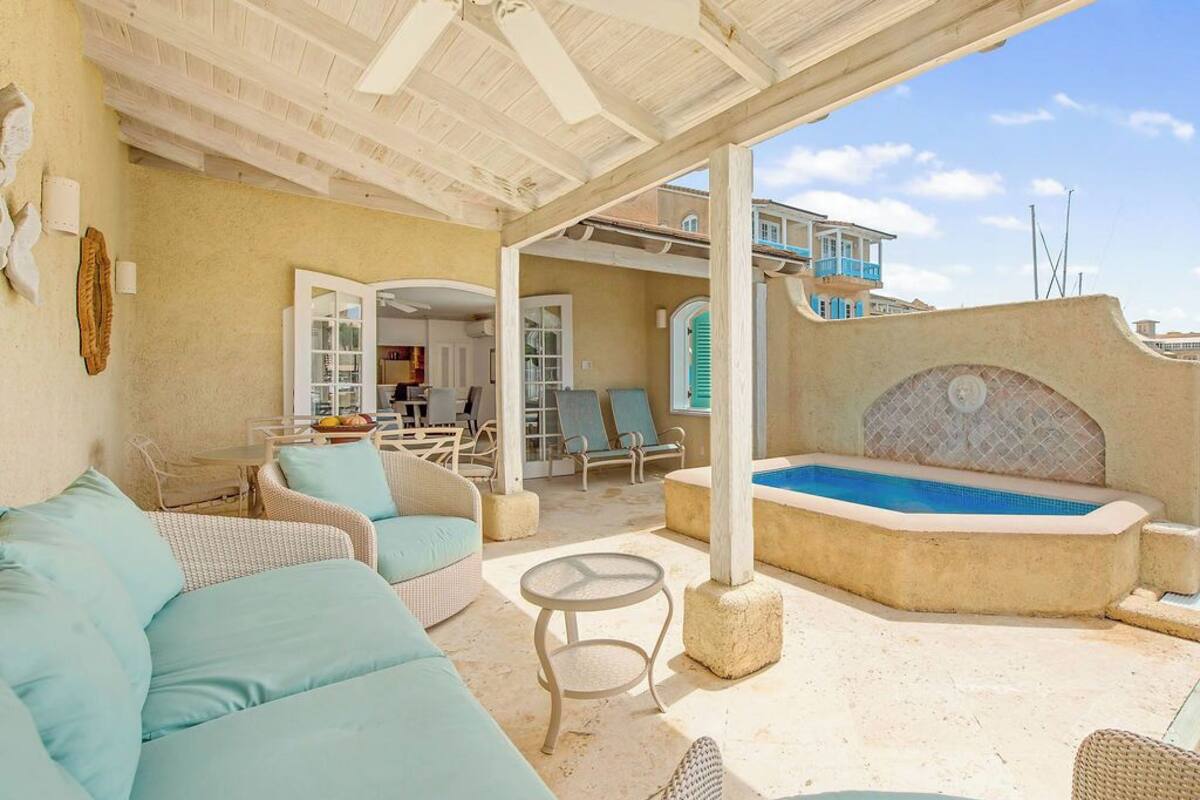 Un patio al aire libre con piscina, zona de estar y una sección cubierta.