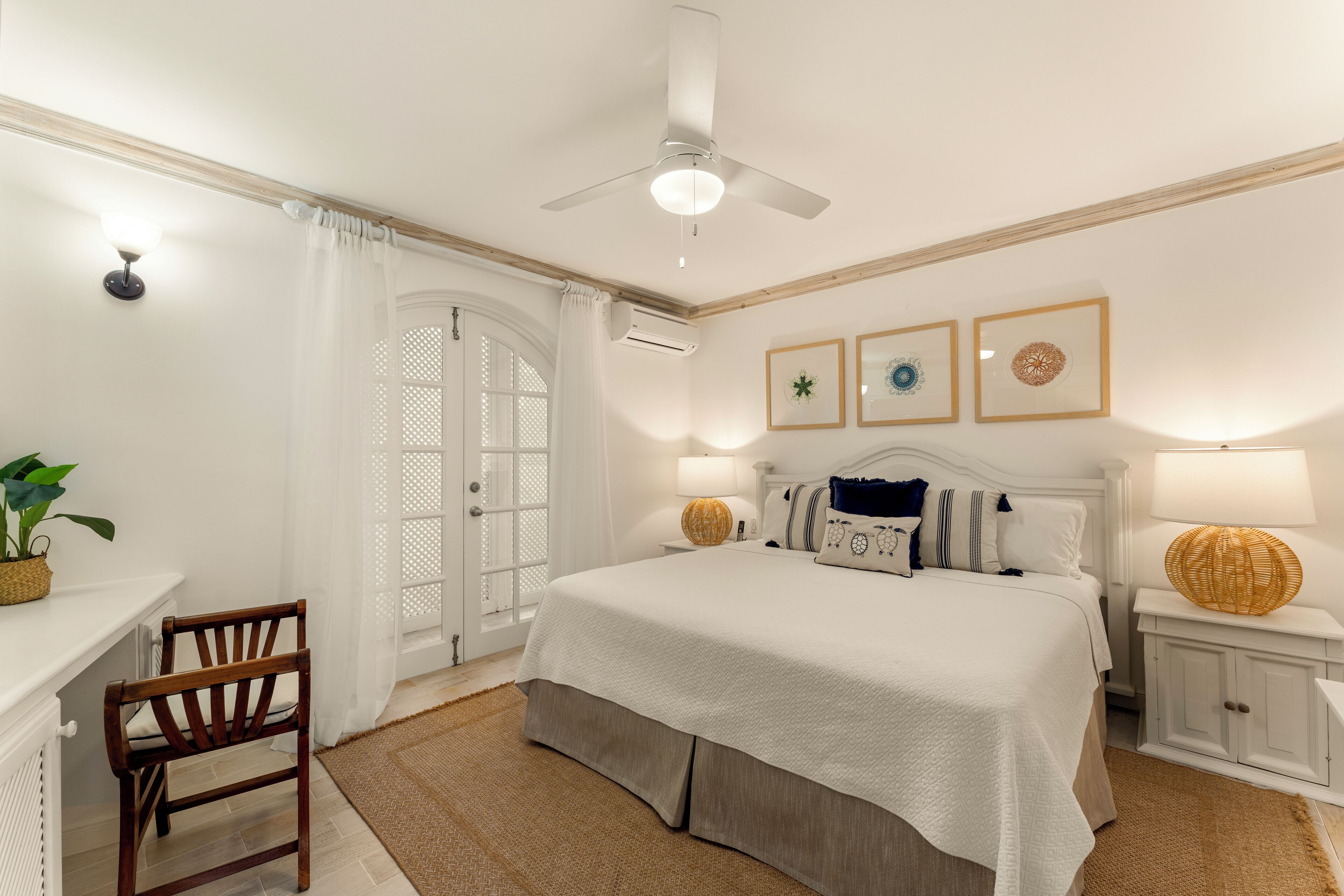 A bedroom with a bed, a chair, a desk, a ceiling fan, and wall-mounted lamps.