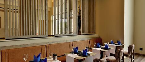 Un restaurante con mesas y cabinas, cada una con servilletas y copas de vino azules.