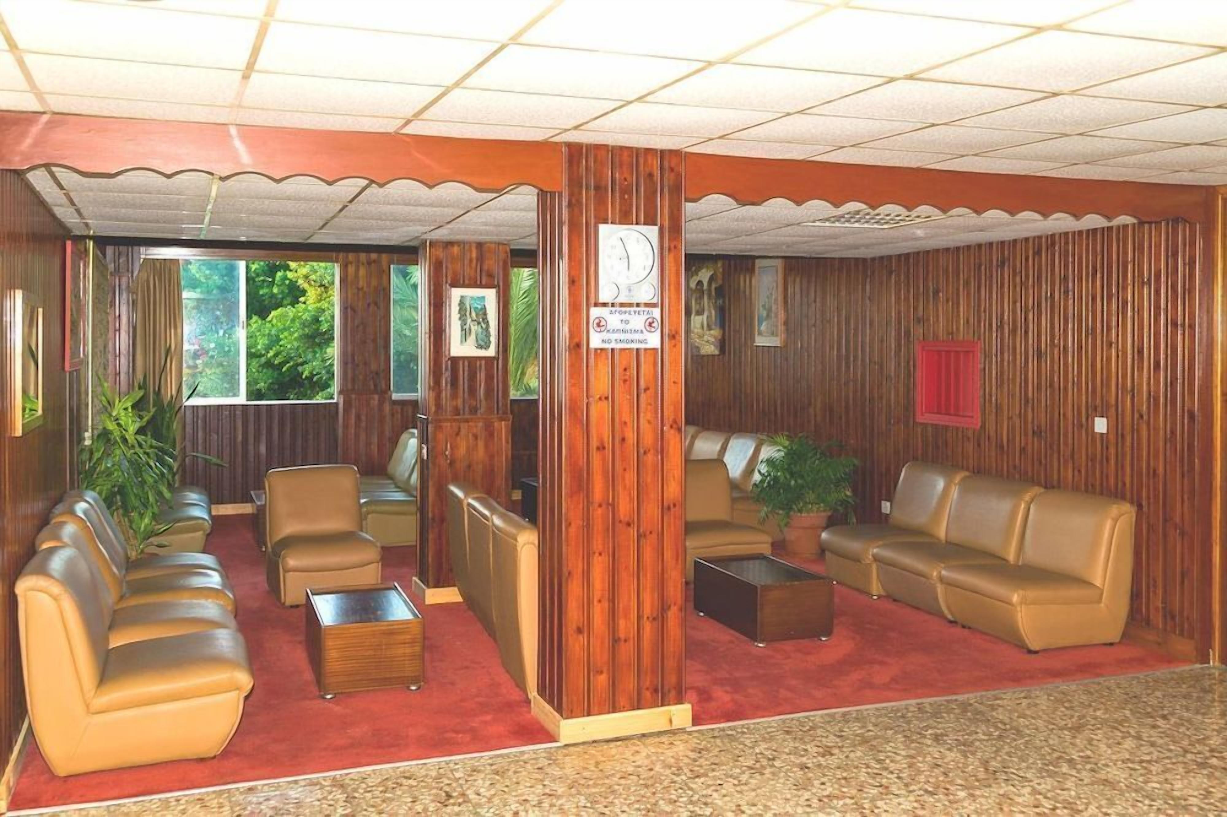 Un hall d’entrée avec des boiseries, des canapés en cuir, une horloge et une moquette rouge.