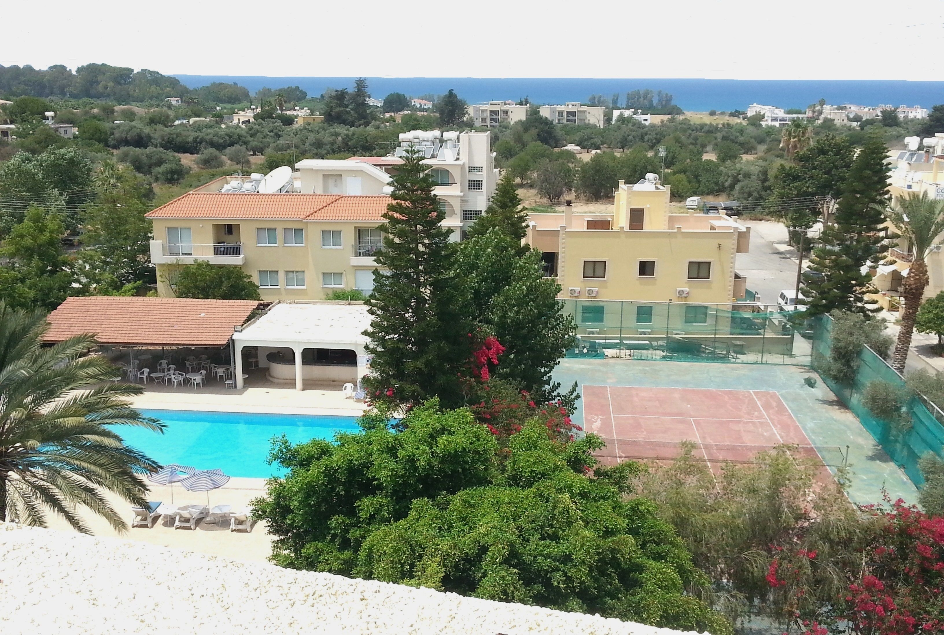 A residential area with a swimming pool, tennis court, and surrounding greenery.