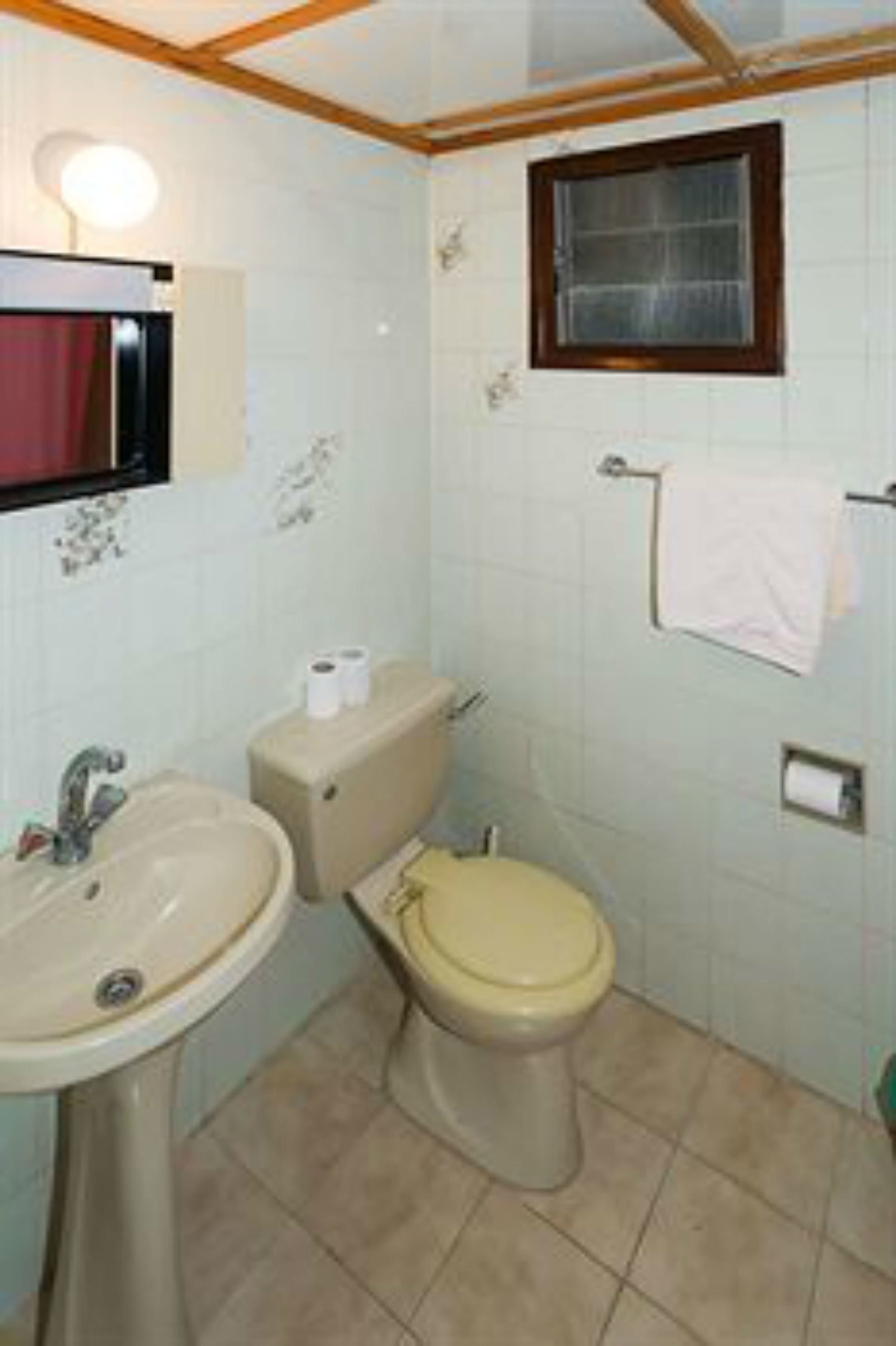 A small bathroom with a sink, toilet, and a mirror.