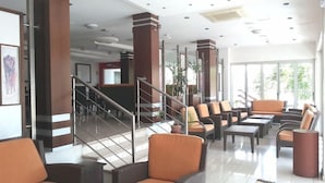 A spacious lobby with a staircase, seating area, and large windows. - Marion (Polis)