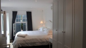 A bedroom with a bed, a nightstand, a lamp, and a wardrobe. - Beauclair Guest Cottage (Stellenbosch)